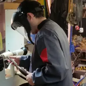Beginner learning woodturning at a lathe during a practical tuition session.