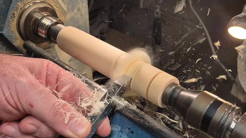 parting tool cutting spindle on wood lathe with shavings flying