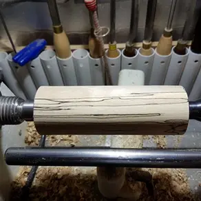 a blank mounted on a jet lathe with tools in holders behind
