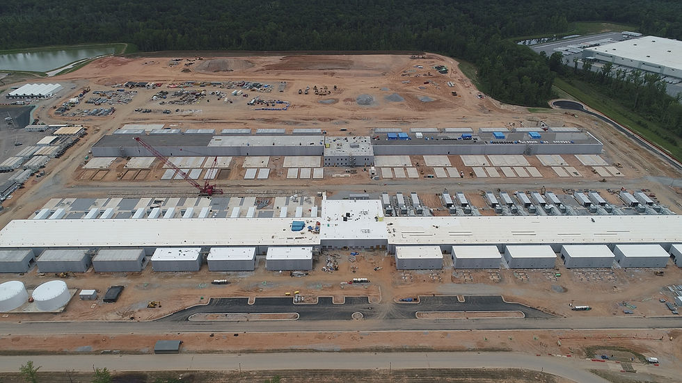 A large data center campus under construction — rows of identical concrete buildings stretch across a Georgia site, with active earthwork visible around the perimeter