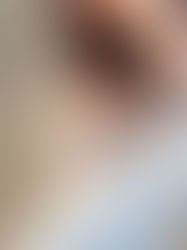 Woman in sunglasses holds hand on a beach, waves in the background. She's wearing a brown top and white skirt, creating a joyful mood.