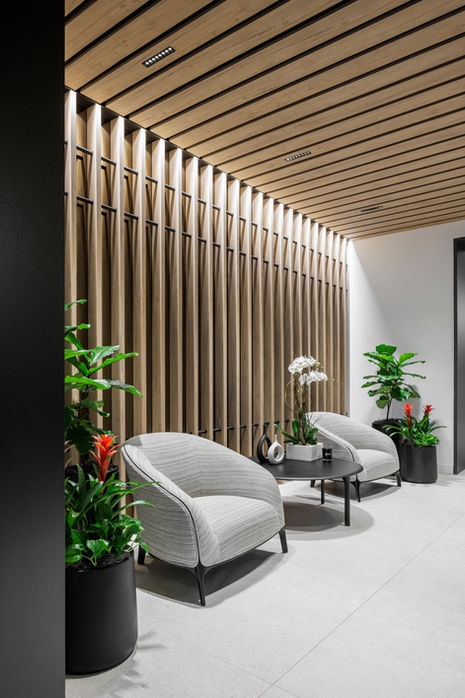 a waiting room with chairs and plants and a wooden wall
