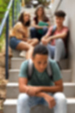 A group of teenagers standing behind a sad child
