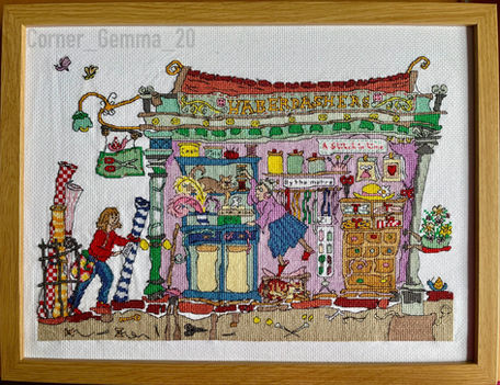 A cross-stitched framed picture of the inside of a haberdashery. Lots of colours and beautiful textures.
