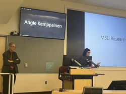 A woman stands at a podium giving a presentation.