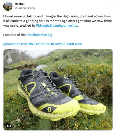 A pair of worn running shoes on grass in the Highlands, Scotland. Shoes are black and yellow. Background shows mossy rocks and trees.