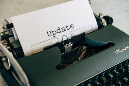 A vintage typewriter with a white paper displaying the word "Update." The atmosphere is nostalgic with a focus on communication.