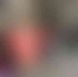 Three people stand outside a stone building. Two hold a banner reading "1 in 4 people with ME is BEDBOUND." They wear red shirts.