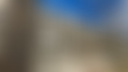 Sign for United States Department of Labor in front of a large beige building. Clear blue sky and sparse trees in the background.