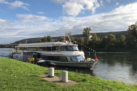 Weißes Passagierschiff am grasbewachsenen Flussufer