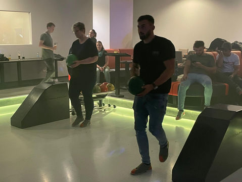 Zwei Personen mit Bowlingkugeln auf einer Bowlingbahn.