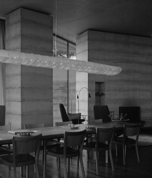 Black and white photo of the dining and living area inside the Secular Retreat by Peter Zumthor, emphasizing minimalist design and natural light.