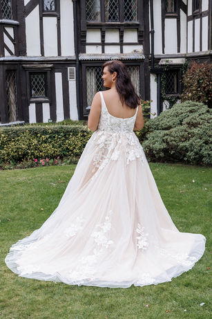 A blush square neck wedding dress made from lace and tulle with detachable lantern sleeves with lace decoration and a long train.