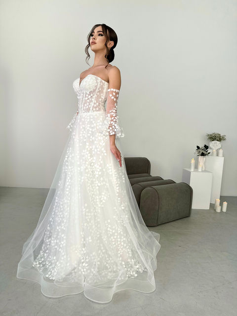 A fabulously unique a line style with 3D flowers beneath a tulle underlay, a structured sweetheart bodice and adjustable corset back. This wedding dress also has a light train and a horsehair trim.