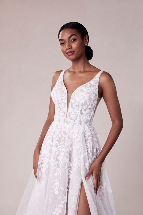 Our Song designer wedding dress is a symphony of beauty. The flowing A-line gown has a sculptured v-neckline that draws the eye down in a sultry plunge with beautiful beaded trim and a matching v-shape back that shows off the perfect amount of skin. Embroidered lace has a botanical design, featuring pops of three-dimensional appliqués, over the floral motif of romantic Chantilly lace.