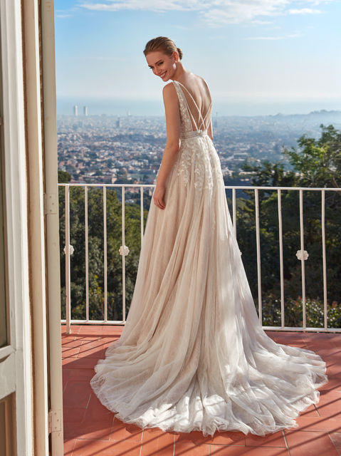 Tulle design with Chantilly lace, embroidery, and beadwork. The A-line silhouette and V-neckline with open back offer a fresh, sophisticated proposal for a confident bride.