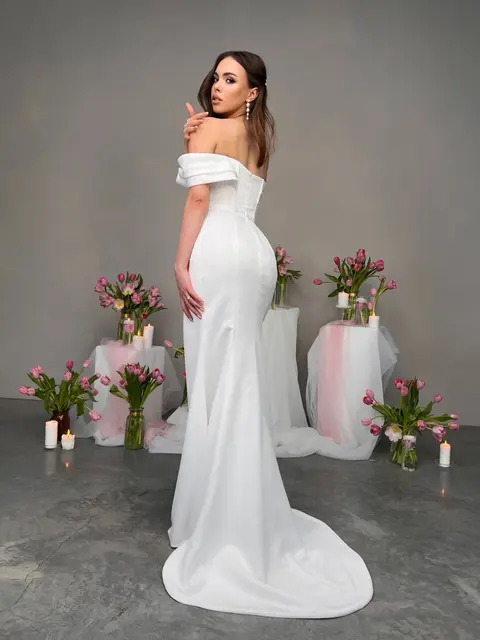 This seductive satin sheath wedding dress features a high slit, asymmetric off shoulder neckline, boned gathered bodice and short train.