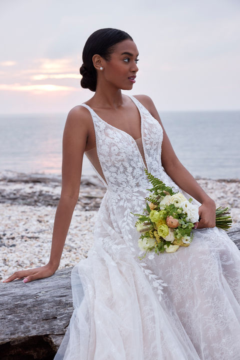 Our Song designer wedding dress is a symphony of beauty. The flowing A-line gown has a sculptured v-neckline that draws the eye down in a sultry plunge with beautiful beaded trim and a matching v-shape back that shows off the perfect amount of skin. Embroidered lace has a botanical design, featuring pops of three-dimensional appliqués, over the floral motif of romantic Chantilly lace.