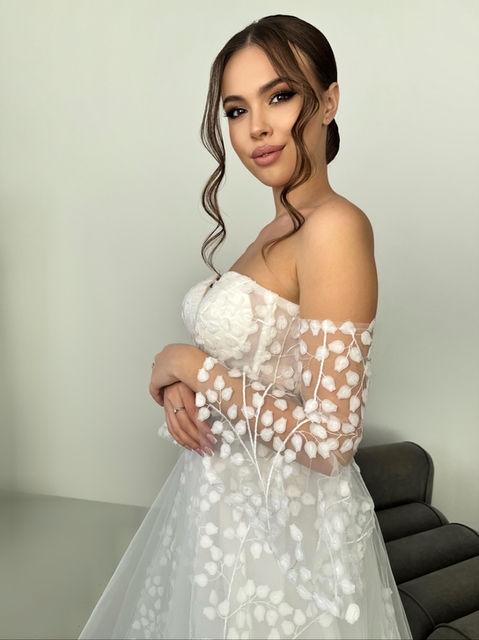 A fabulously unique a line style with 3D flowers beneath a tulle underlay, a structured sweetheart bodice and adjustable corset back. This wedding dress also has a light train and a horsehair trim.