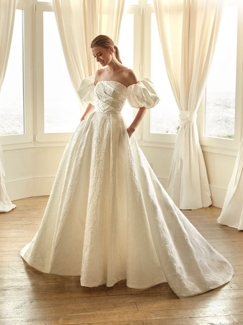 Princess silhouette design in jacquard with a strapless neckline. Its structure and volume make it a majestic choice for a bride who wants to stand out with elegance.