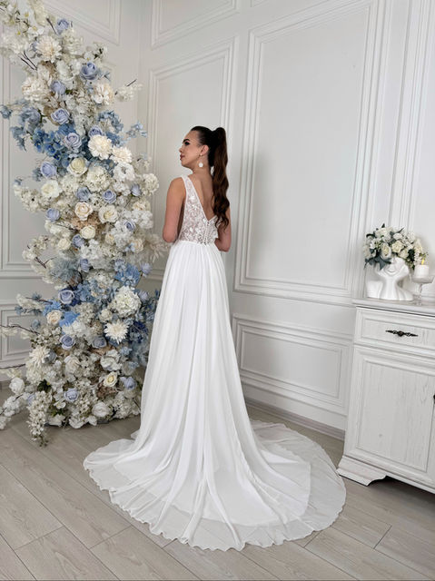 Anabel features a lightweight chiffon shirt with a long train and a boned bodice with a deep v neckline and side cutouts. The bodice is beautifully decorated with lace, sequins and 3D flowers.