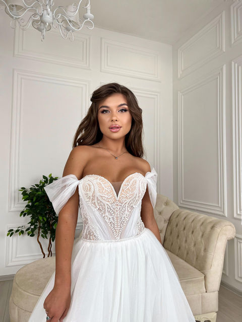 A fairytale princess wedding dress with a full glitter tulle skirt, sweetheart neckline, tulle off-shoulder straps and a beaded bodice with lace decoration. This dress has no train.