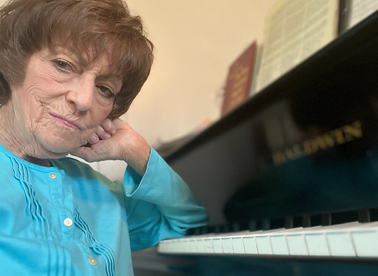 Dr. Lucas sitting at her piano looking kindly into the camera