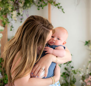 Mother smiling down at her baby during a floral studio session at Lemon Drop Studios in McKinney, TX — tender family moment.
