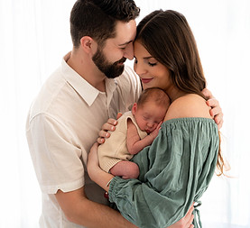 Parents lovingly hold their newborn in a bright studio during a Frisco newborn photography session.