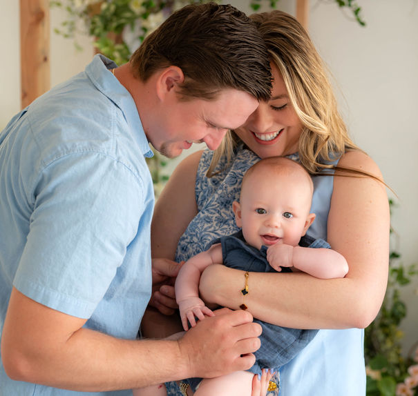 Parents smiling with their baby during a cozy studio session at Lemon Drop Studios in McKinney, TX — tender newborn family moment.