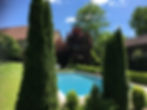 La piscine avec l`eau salée bleu dans la jardin entouré d`arbres, de transats et parasols