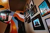 Colorful staircase wall at Dar Baba in Essaouira, featuring abstract murals and a gallery of framed surrealist art.