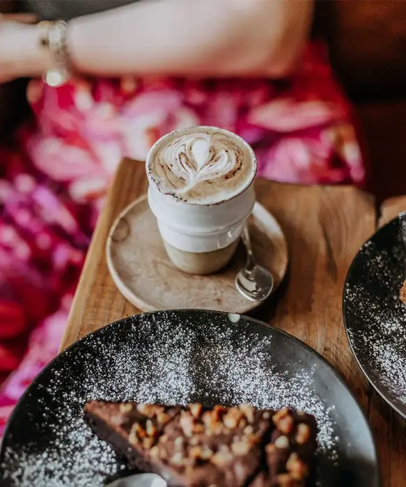 Artisan latte with heart-shaped latte art, served with a rich vegan chocolate dessert at Mandala Society café.