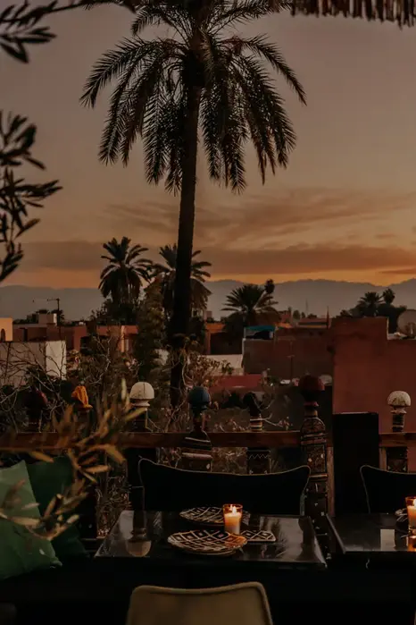 Palm tree and candlelit table at Blackchich rooftop with medina sunset view