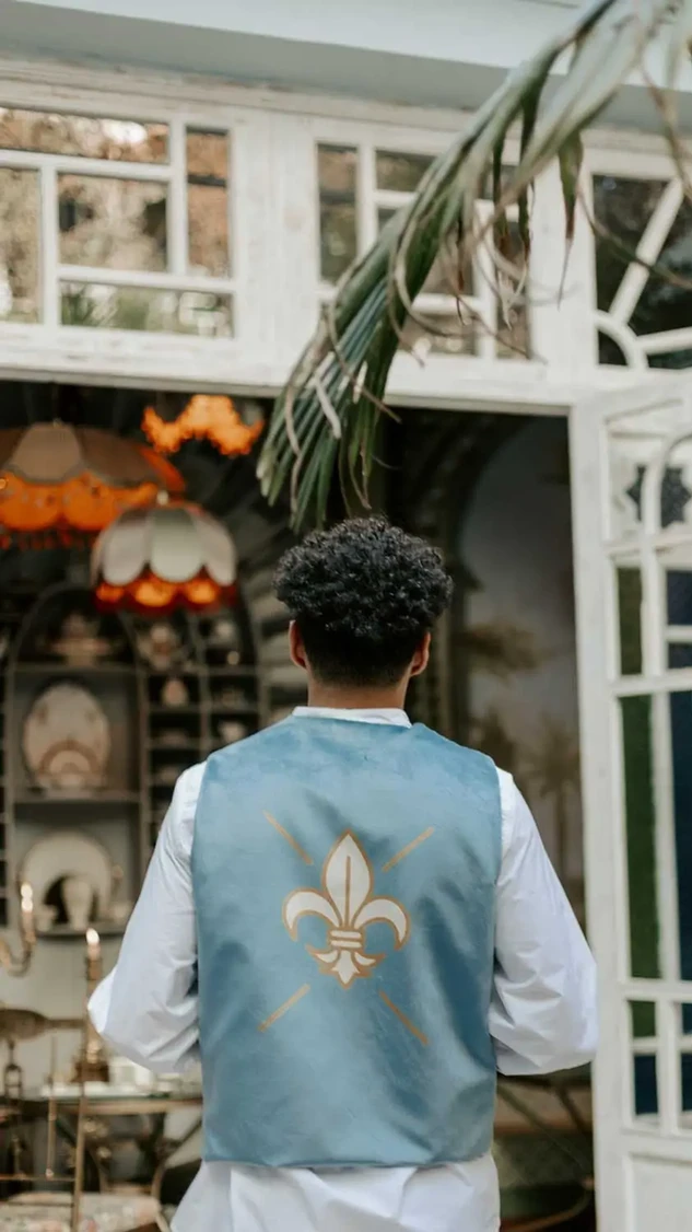 Villa Aaron waiter entering through carved archway, wearing fleur-de-lis vest at the restaurant entrance in Marrakech