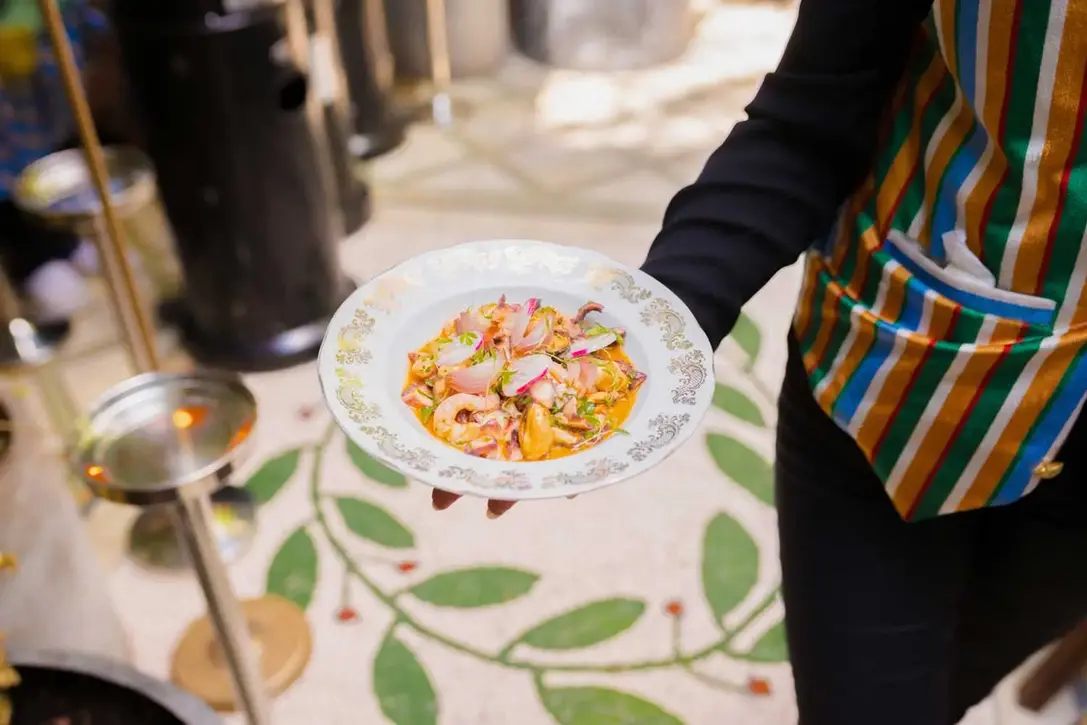 Waiter in colorful vest serving seafood dish with radish at Villa Aaron