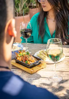 Des amis partagent un plat de fruits de mer et du vin au restaurant sur le toit Kabana à Marrakech, profitant d'une expérience culinaire en plein air.