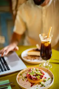 Raspberry tart and iced coffee at Kabana rooftop Marrakech – colorful dessert moment with laptop open on table
