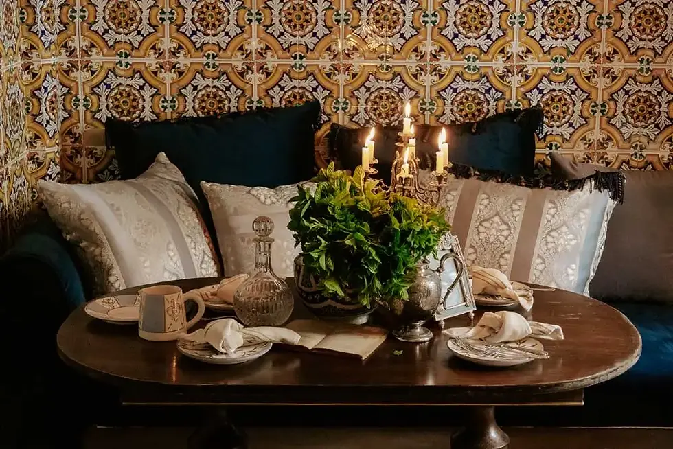Coin repas intime à la Villa Aaron Marrakech avec carrelage marocain traditionnel, coussins en velours, candélabres et vaisselle élégante