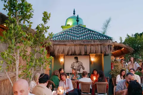 Guests dining on Kabana’s rooftop at sunset with Moroccan décor and warm ambiance.