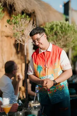 Serveur de Kabana Marrakech souriant et servant les clients sur une terrasse ensoleillée sur le toit