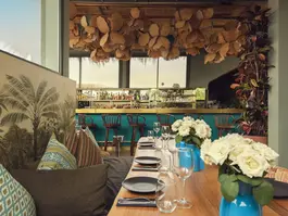 Rooftop dining table setup at Kabana Marrakech with view of the cocktail bar and decorative ceiling lights.