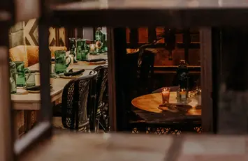 Warm candlelit table setting inside Blackchich restaurant seen through window