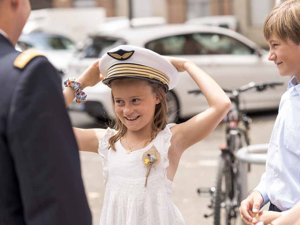 Une jeune demoiselle d'honneur se coiffe de la casquette du témoin, en uniforme de l'armée de l'air.