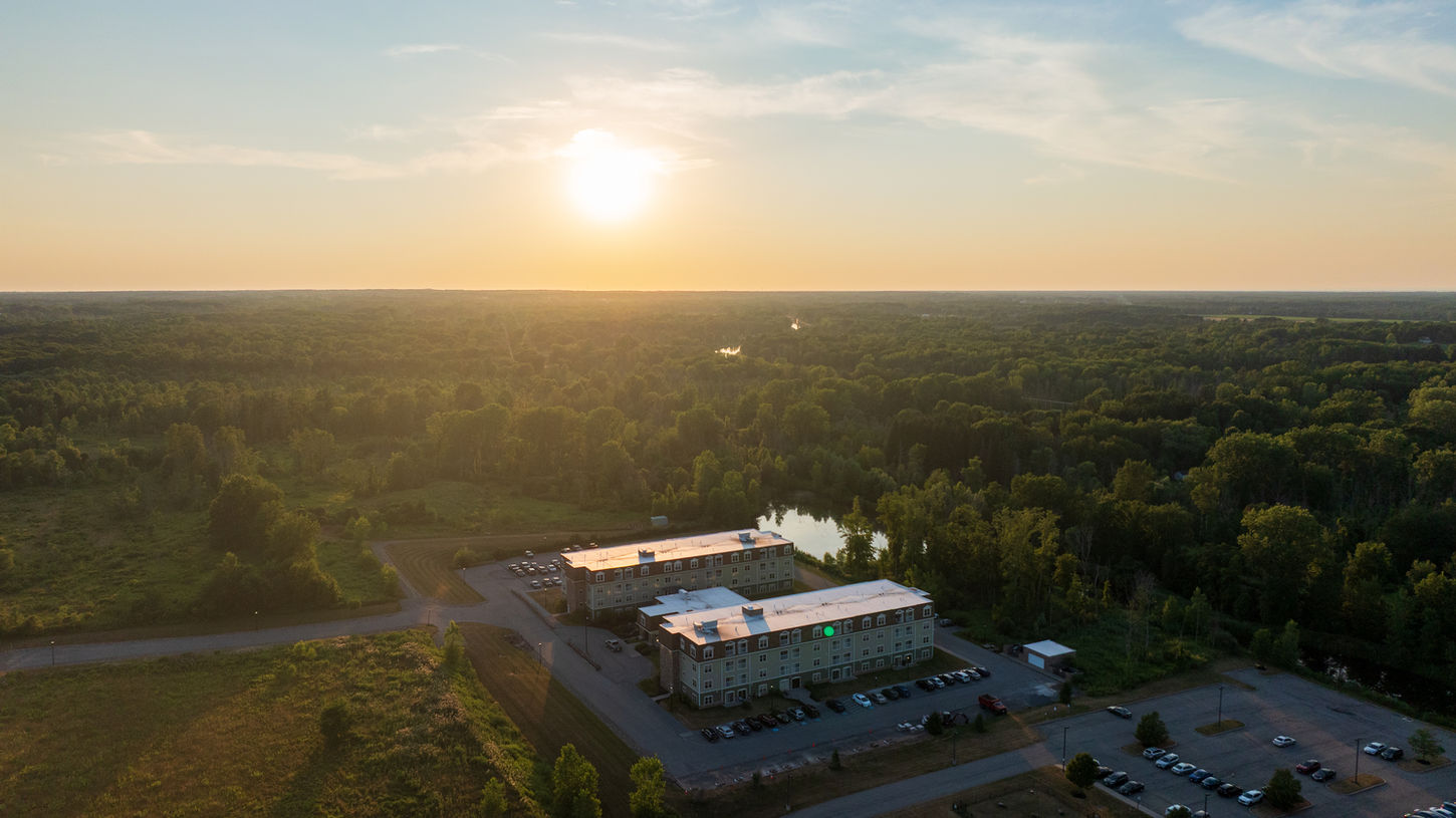 Drone view of Chateau at Heritage Square 55+ community at sunset with trees behind