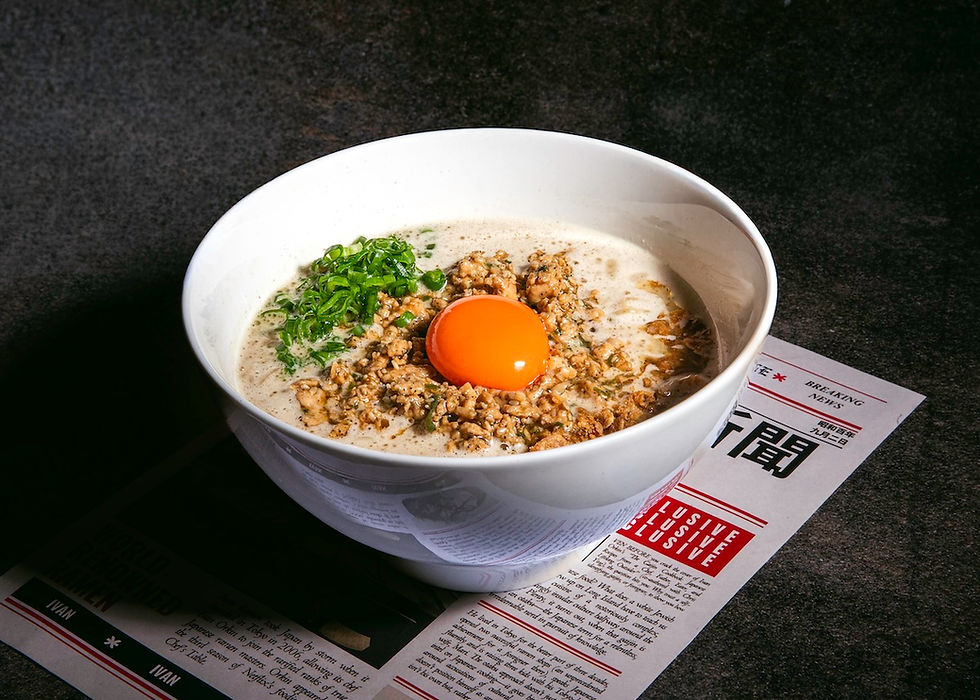 A bowl of ramen with minced meat, a raw egg yolk, and green onions. The bowl rests on a newspaper with visible text, on a dark surface.