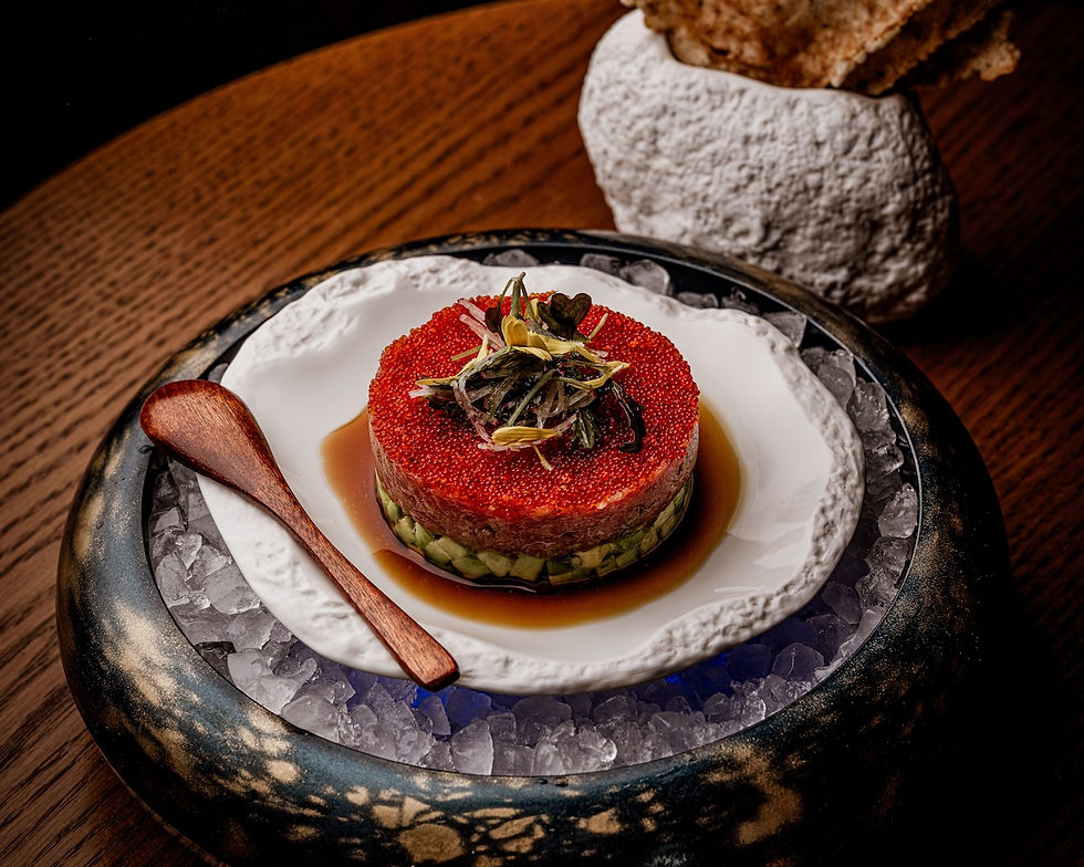 Gourmet dish on ice, featuring red caviar and garnish on a white plate with a wooden spoon. Elegant setting, brown table background.