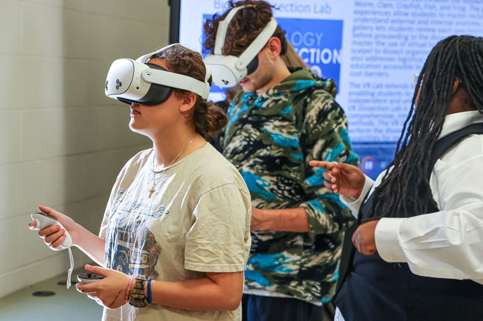 People using VR headsets, with a guide Adrian providing instructions.