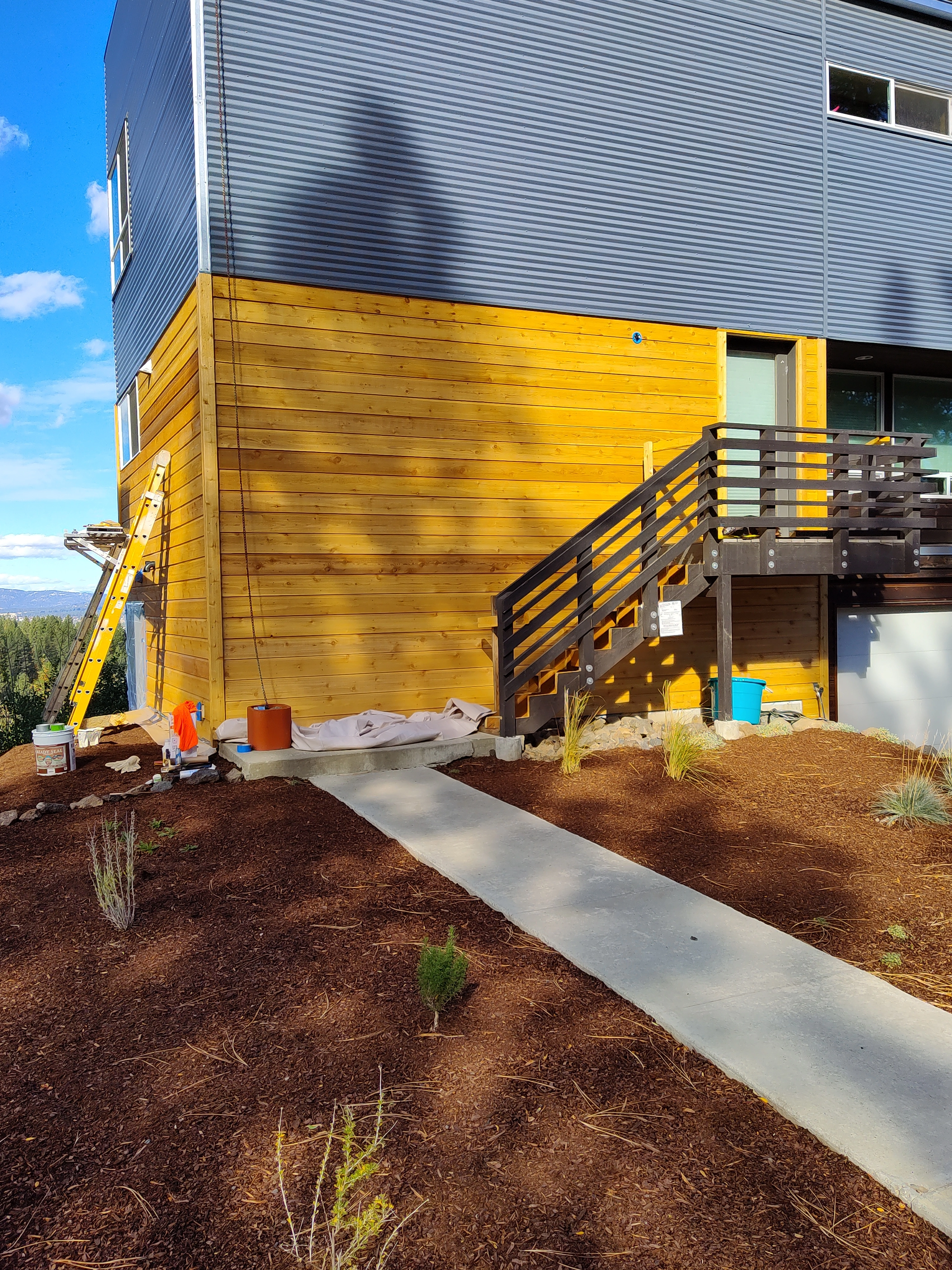 Completed wood siding repair and installation project on a mountain-side home in Spokane, Washington. The image features a ladder leaning on the newly installed wood siding, showcasing the attention to detail and craftsmanship. The stunning mountainous backdrop adds to the beauty of the finished work.