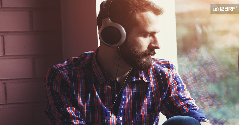 Stock Photo - stylish bearded man in headphones listening to music near window with reflection